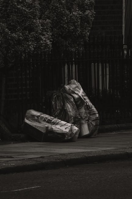 The image displays a collection of metal debris and discarded construction materials spread across a paved outdoor area, possibly a driveway or storage yard. Among the items are metal sheets with roug
